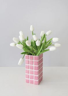 a pink vase with white tulips in it