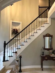 a staircase leading up to a foyer with a mirror and vase on the table next to it