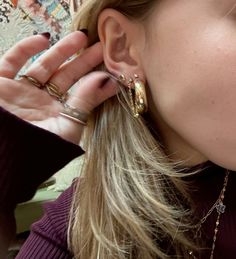 a close up of a person with ear rings on their ears and one hand in the other's ear