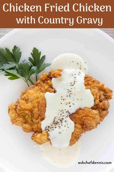 a white plate topped with fried chicken covered in sauce and garnished with parsley