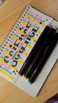 two pens sitting on top of a spiral notebook