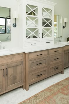 a large bathroom with two sinks and wooden cabinets in front of the mirror on the wall