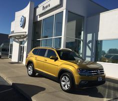 a yellow volkswagen suv parked in front of a dealership