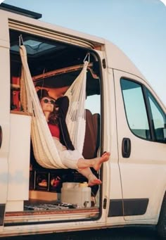 a woman sitting in a hammock on the back of a van