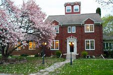 a red brick house with flowering trees in the front yard and steps leading up to it