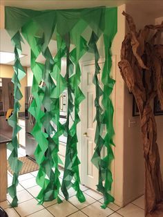 an open door with green paper hanging from it's side and trees on the other side