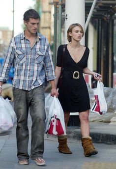 a man and woman walking down the street with bags in their hands, carrying shopping bags