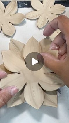 two hands are working on some wooden flowers