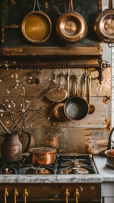 pots and pans are hanging on the wall above an oven in a rustic kitchen