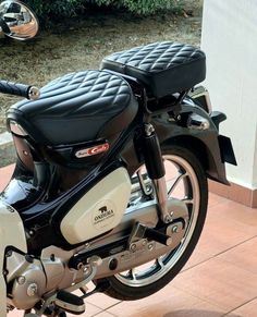 a black and white motorcycle parked in front of a building on a brick sidewalk next to bushes