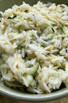 a bowl filled with rice and cucumbers on top of a table