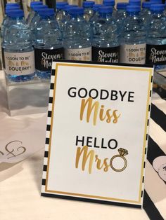 there is a sign that says goodbye miss hello mrs and bottles of water behind it