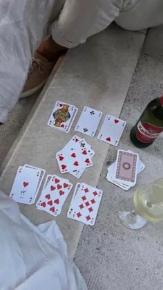 playing cards on the floor next to a bottle of wine and some glasses with champagne