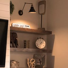 two shelves with various items on them and a clock above the shelf in the corner