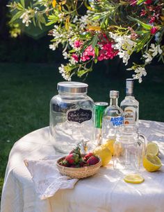 the table is covered with lemons, strawberries, and bottles of gin on it