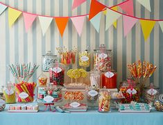 an assortment of candy and candies displayed on a table in front of striped wallpaper