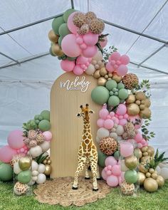 a giraffe standing in front of a tall cake with balloons on it's side