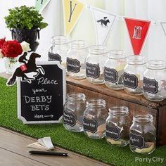 there are many jars on the table with chalkboard signs and flowers in vases