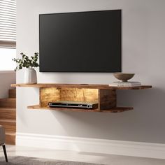 an entertainment center with a flat screen tv mounted on the wall and shelves below it