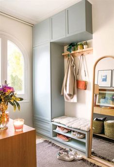 a room with a mirror, coat rack and flowers on the table in front of it