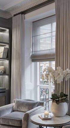 a living room filled with furniture next to a window covered in white drapes and curtains