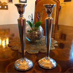 two silver candlesticks sitting on top of a table next to a vase filled with flowers