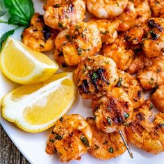 a white plate topped with shrimp and lemon wedges