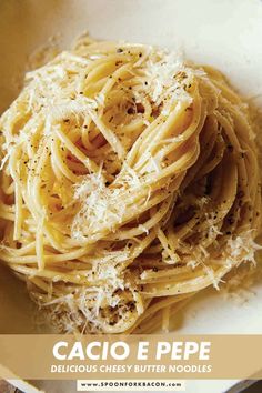 a white bowl filled with pasta covered in parmesan and seasoning on top of a wooden table