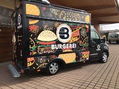 a black food truck parked in front of a building with burger written on the side