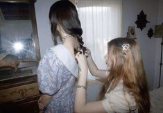 two girls are getting their hair done in front of a mirror with the light shining on them