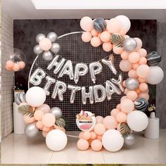 a happy birthday sign surrounded by balloons and streamers in a room with tiled walls