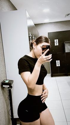 a woman is taking a selfie in the bathroom while wearing shorts and a black shirt