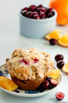 a muffin on a plate with oranges and cherries