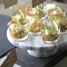 small glasses filled with food sitting on top of a marble platter covered in garnishes