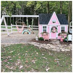 a pink and white house with a hammock swing in the yard next to it