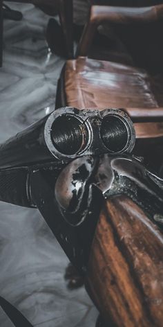 an old pair of binoculars sitting on top of a wooden bench next to a chair