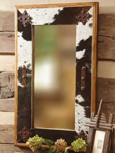 a cow print mirror sitting on top of a wooden shelf next to a potted plant