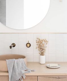 a bathroom with a round mirror above the sink