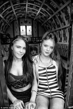 two young women sitting on the back of an old train car in black and white