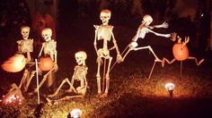 halloween decorations made to look like skeletons and pumpkins in the yard at night time