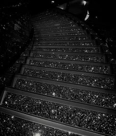 the stairs are covered in snow at night, with lights shining on them and stars falling down