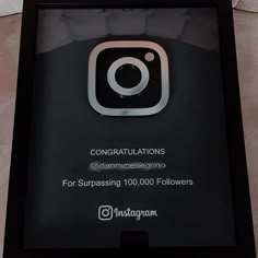 an instagram sign is displayed on the floor in front of a white wall with a black frame