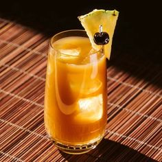 an alcoholic drink on a table with a slice of pineapple