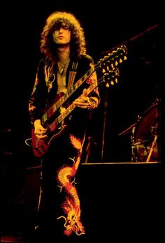 a man with long hair playing an electric guitar