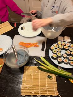 two people preparing sushi rolls on a table