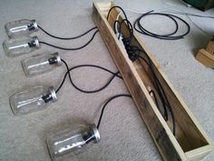 four empty wine glasses sitting on the floor next to a wooden box with wires in it