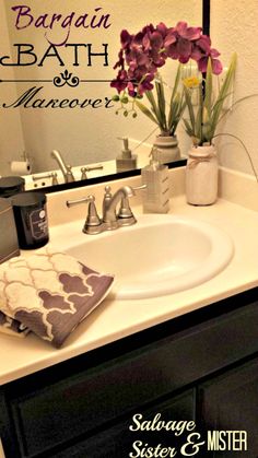 a bathroom sink sitting under a mirror next to a vase with flowers