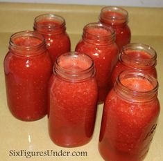 several jars filled with red liquid sitting on top of a counter