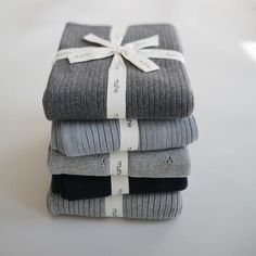 three folded gray and black sweaters tied with a white ribbon on top of each other