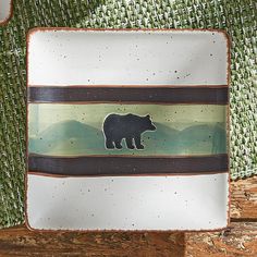 a bear plate sitting on top of a wooden table next to a green cloth covered wall